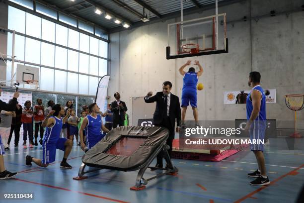 French President Emmanuel Macron gestures as he takes part in display of basketball skills during a visit at the Jesse Owens gymnasium in...