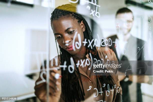 writing mathematical formulas on transparent wipe board - mathematics stock pictures, royalty-free photos & images