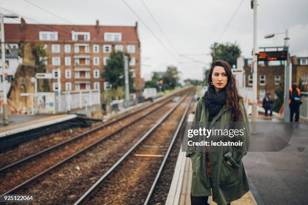 tired young woman waiting for the public transportation in london, uk - parka coat stock pictures, royalty-free photos & images