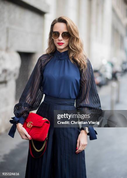 Alexandra Lapp wearing black flared pants and a matching blouse with transparent arms from Nobi Talai, sunglasses from Maison Mavada and a red velvet...