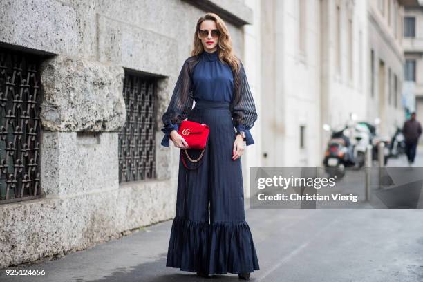 Alexandra Lapp wearing black flared pants and a matching blouse with transparent arms from Nobi Talai, sunglasses from Maison Mavada and a red velvet...