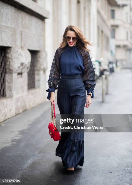 Alexandra Lapp wearing black flared pants and a matching blouse with transparent arms from Nobi Talai, sunglasses from Maison Mavada and a red velvet...