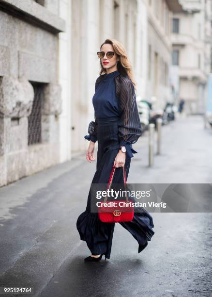 Alexandra Lapp wearing black flared pants and a matching blouse with transparent arms from Nobi Talai, sunglasses from Maison Mavada and a red velvet...