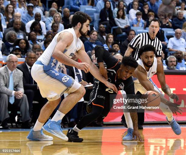 Chris Lykes of the Miami Hurricanes loses the ball as he drives between Luke Maye and Joel Berry II of the North Carolina Tar Heels during their game...