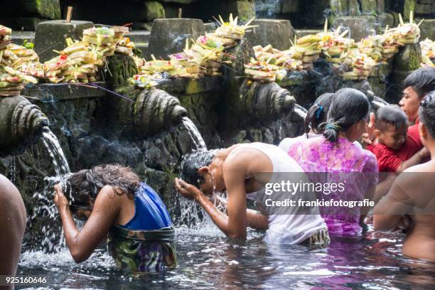 tourists bathing in the holy water at pura tirta empul temple, tampaksiring, bali, indonesia - tirta empul temple stock pictures, royalty-free photos & images