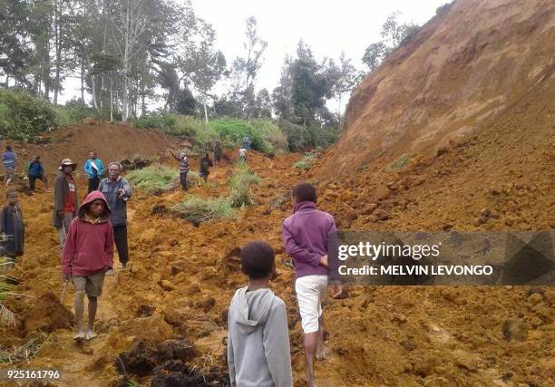 This photo taken on February 27, 2018 and received on February 28 shows people walking at the site of a landslide near the village of Ekari in Papua...