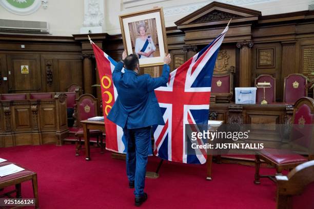 Deputy Superintendent Registrar, Dion Goncalves, moves a portrait of Britain's Queen Elizabeth II into position ahead of a citizenship ceremony at...