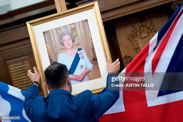 Deputy Superintendent Registrar, Dion Goncalves, moves a portrait of Britain's Queen Elizabeth II into position ahead of a citizenship ceremony at...