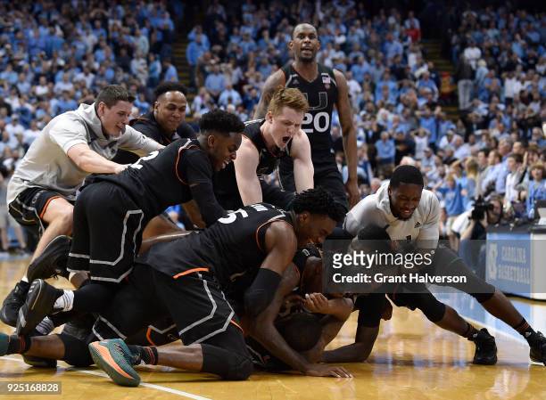 Teammates pile on Ja'Quan Newton of the Miami Hurricanes as they celebrate after his game-wining basket against the North Carolina Tar Heels during...
