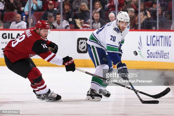 Brandon Sutter of the Vancouver Canucks flips the puck past Christian Dvorak of the Arizona Coyotes during the third period of the NHL game at Gila...