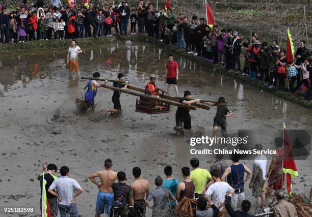 Hakka people carrying a golden statue of ancient Chinese general Guan Yu run on a muddy field to pray for good weather and bumper harvest at Tongfang...
