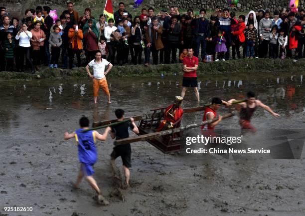 Hakka people carrying a golden statue of ancient Chinese general Guan Yu run on a muddy field to pray for good weather and bumper harvest at Tongfang...