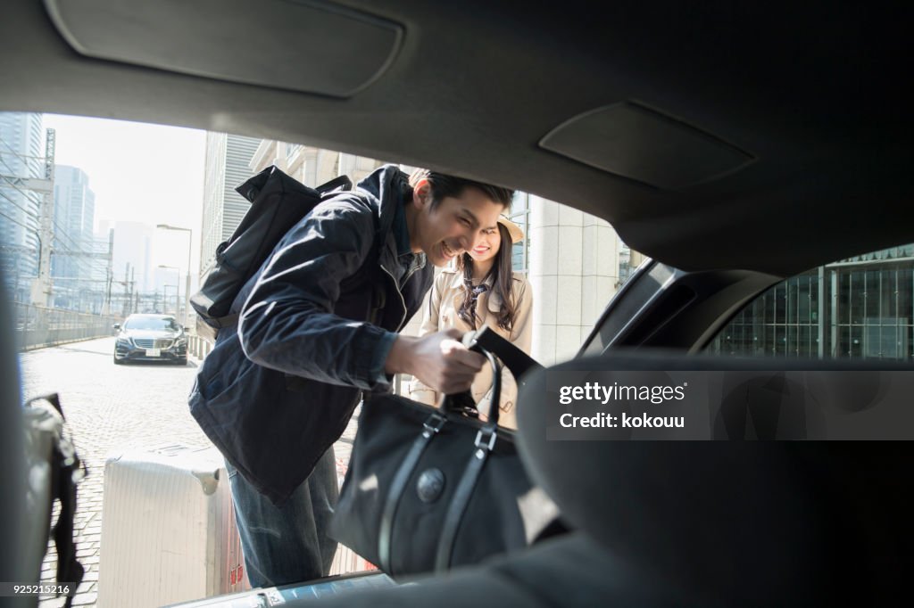 A man who loads luggage in the trunk.