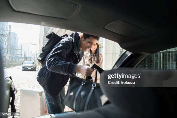 a man who loads luggage in the trunk. - asian couple car stock pictures, royalty-free photos & images