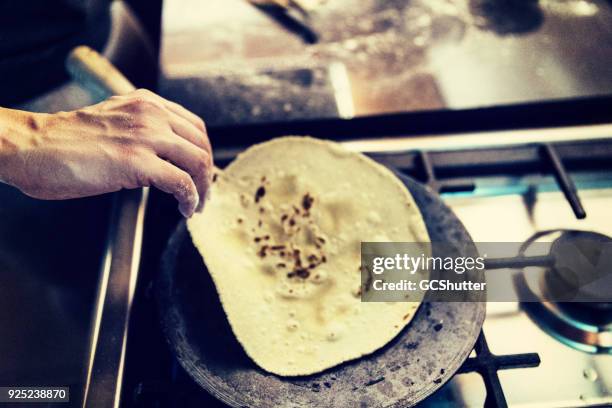 opheffing van een hete chapati uit een pan - rollende keukens stockfoto's en -beelden