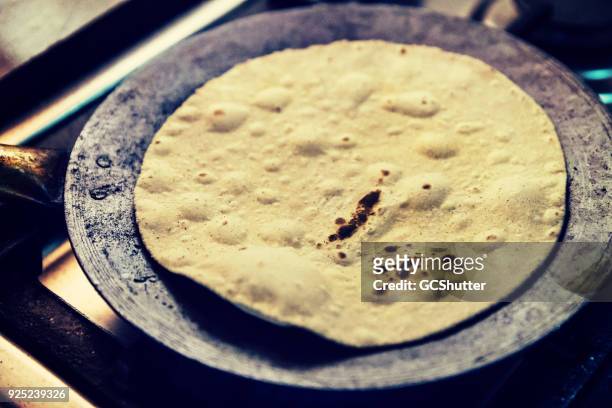 chapati gleichmäßig in einer pfanne erhitzen - emirati lady from back stock-fotos und bilder