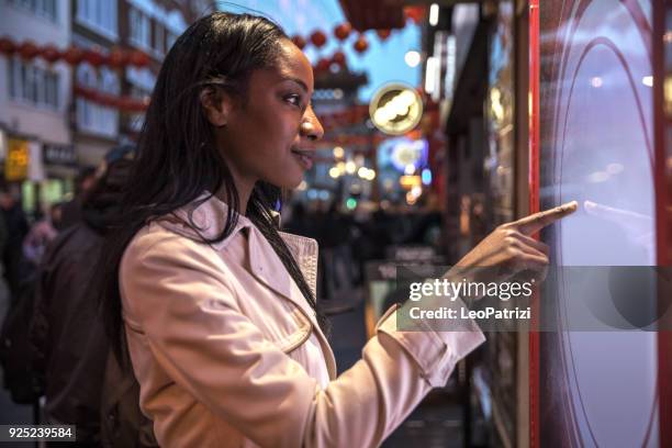 donna che usa un touch screen trovando informazioni online nelle strade della città di londra - città intelligente foto e immagini stock