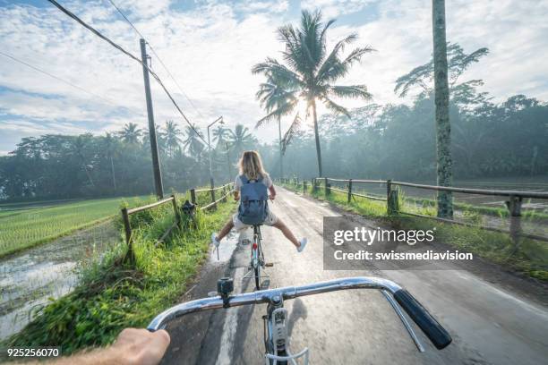 personliga perspektiv-par cykling nära risfält vid soluppgången, indonesien - vinkel bildbanksfoton och bilder