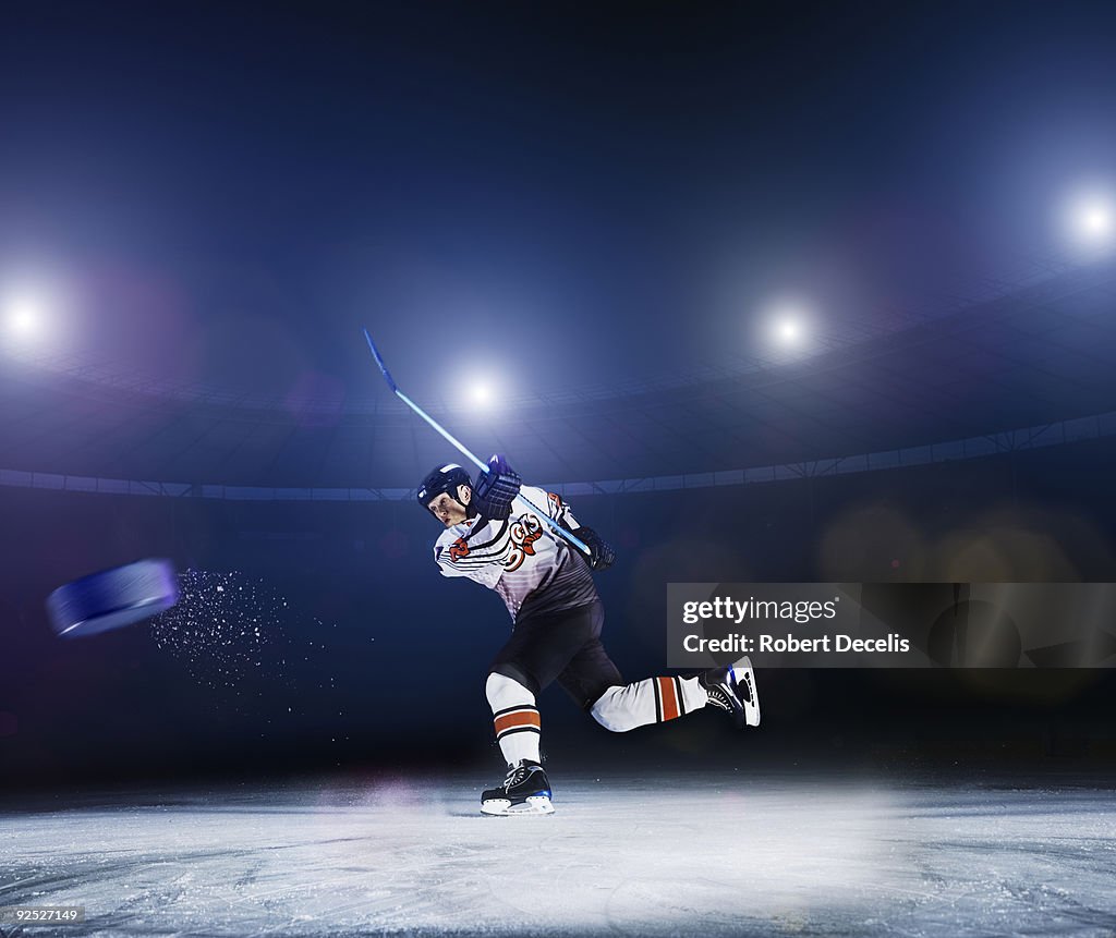 Ice hockey player shooting puck.