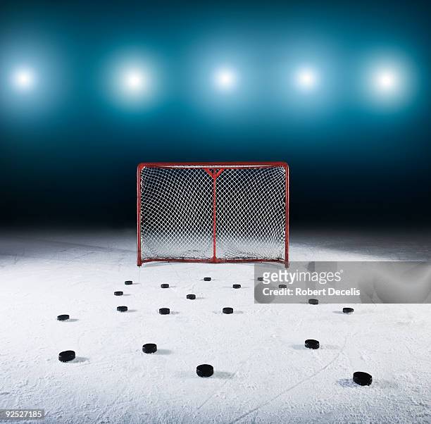 ice hockey goal surrounded by pucks. - ice hockey stockfoto's en -beelden