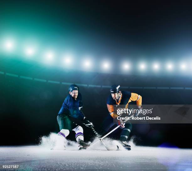 two ice hockey players competing for puck. - eishockey schläger stock-fotos und bilder
