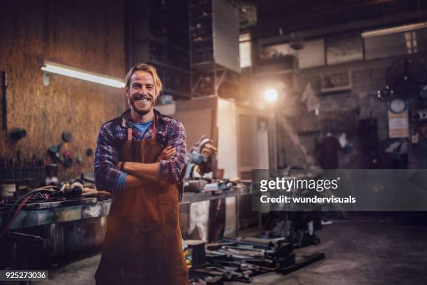 happy professional craftsman standing in workshop with tools - smiling professional at work tools imagens e fotografias de stock