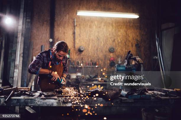 craftsman cutting metal and using angle grinder in workshop - workbench stock pictures, royalty-free photos & images