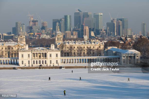 The skyscrapers of Canary Wharf are seen as the sun rises on a snow covered Greenwich Park on February 28, 2018 in London, United Kingdom. Freezing...