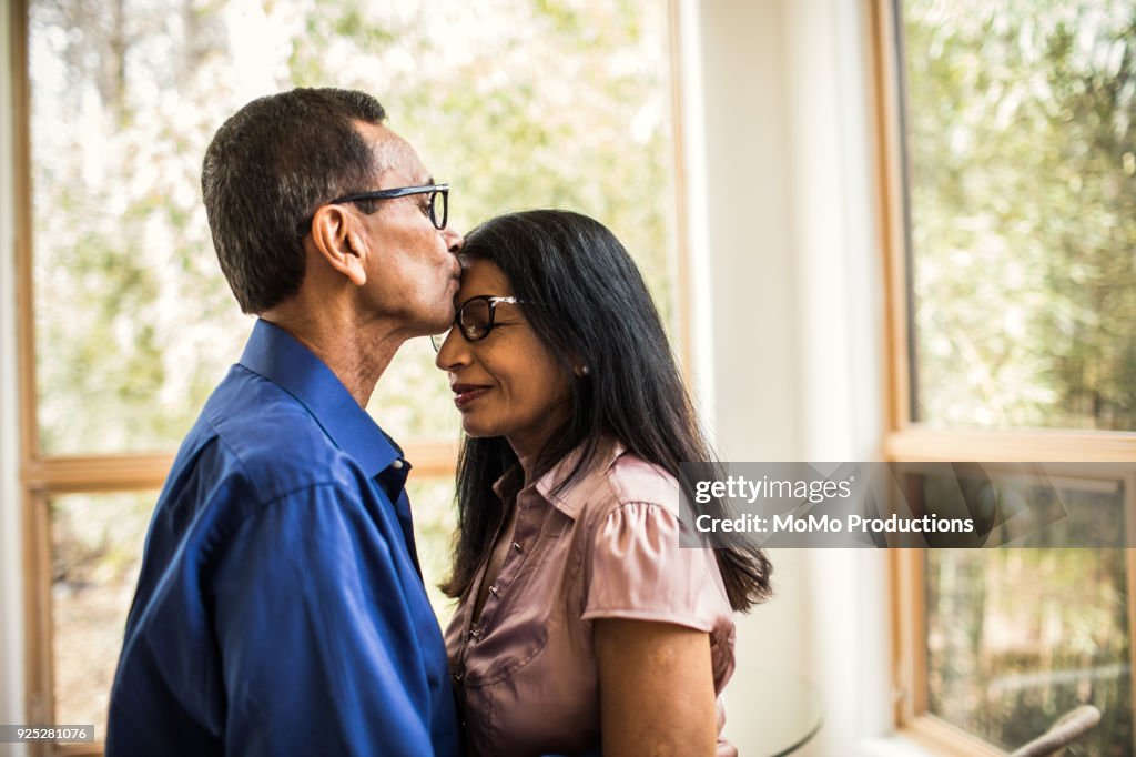 Senior man kissing wife at home