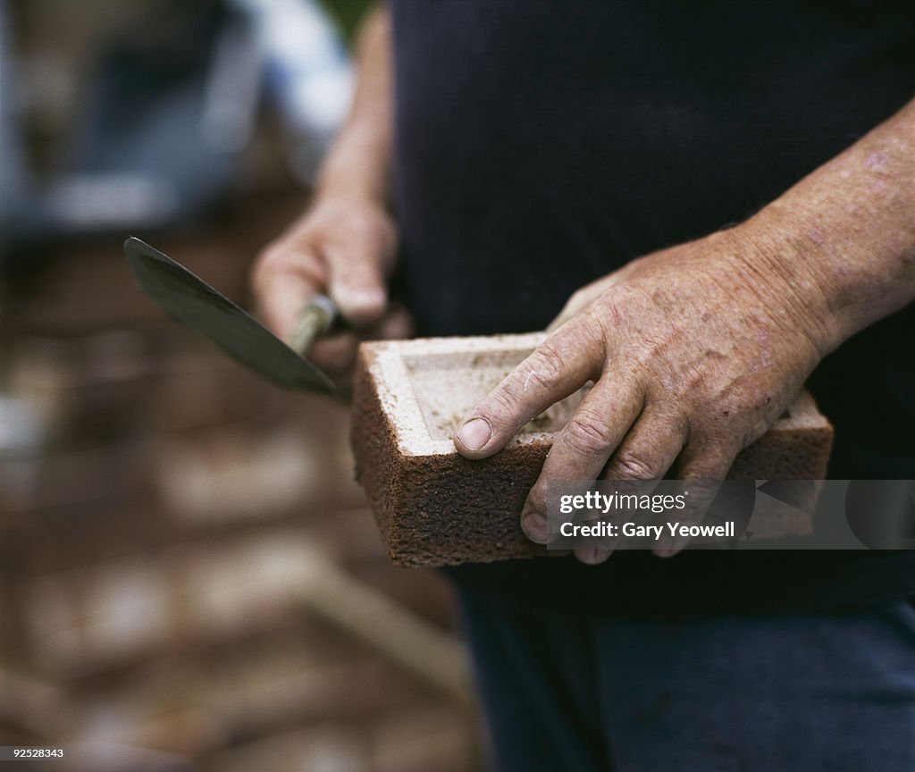 Bricklayer holding a brick and trowel 