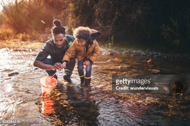 père et fils de pêche au filet dans la rivière de pêche - kids at river photos et images de collection