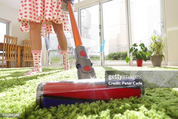 woman vacuuming rug - bored housewife stock-fotos und bilder