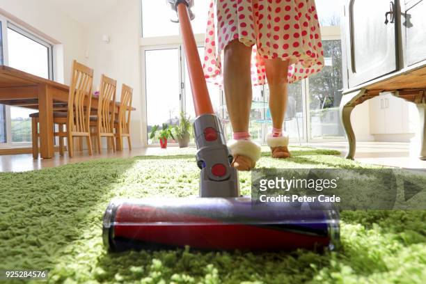 woman vacuuming rug - vacuum cleaner stock-fotos und bilder