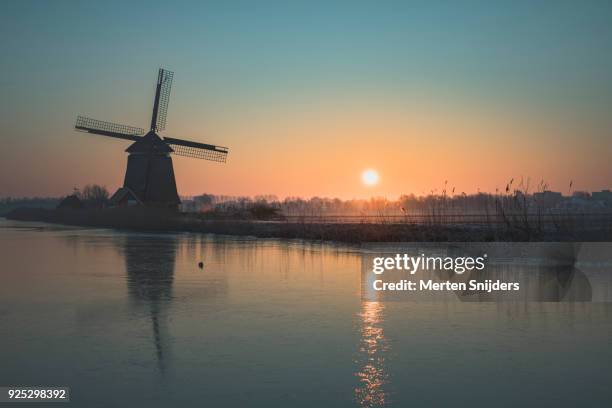 classical dutch windmill amidst frozen countryside - merten snijders stock pictures, royalty-free photos & images