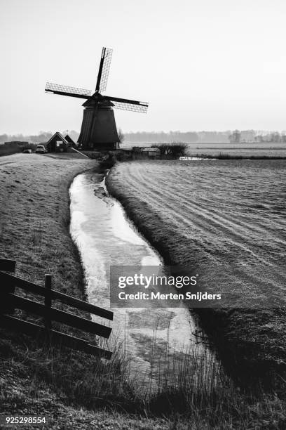 classical dutch windmill amidst frozen countryside - merten snijders stock-fotos und bilder