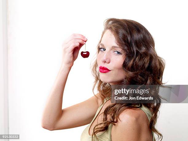 woman about to eat a fresh ripe cherry - monrovia california stockfoto's en -beelden