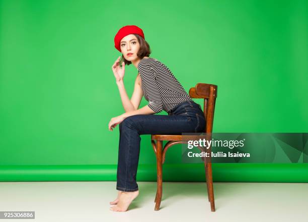 thoughtful woman in beret on chair - bereit photos et images de collection
