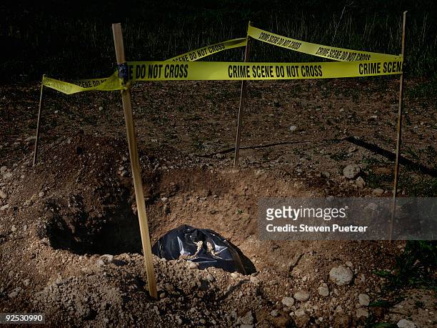 garbage bag in dug hole with crime scene tape - murder foto e immagini stock