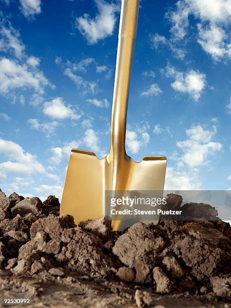 gold shovel in freshly dug dirt with blue sky - shovel stock pictures, royalty-free photos & images