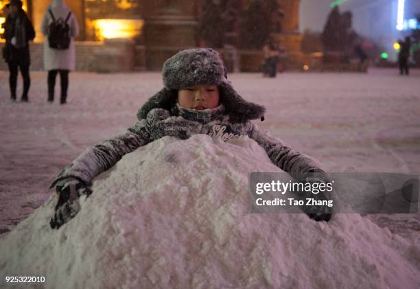 Boy sits coverd with snow in front of Saint Sophia Cathedral as heavy snow and wind hit in Harbin of China ,on February 28, 2018.The meteorological...