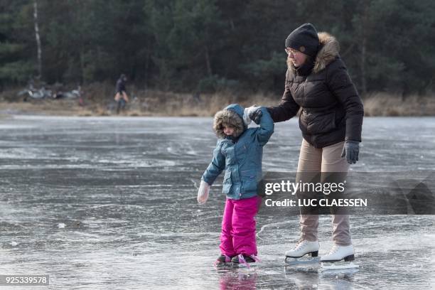 Mother and child ice skate on a frozen lake at the Kalmthoutse heide nature reserve in Kalmthout on February 28, 2018. Europe remained on February 28...