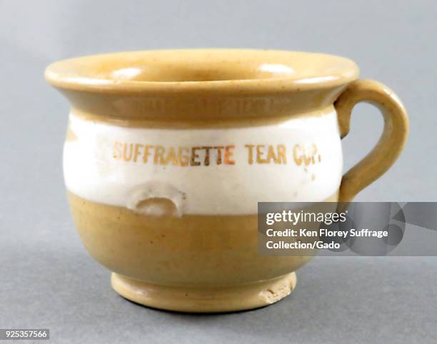 Yellow and white ware, ceramic cup, with a satirical caption on the belly reading "Suffragette Tear Cup", 1900. Photography by Emilia Van Beugen....