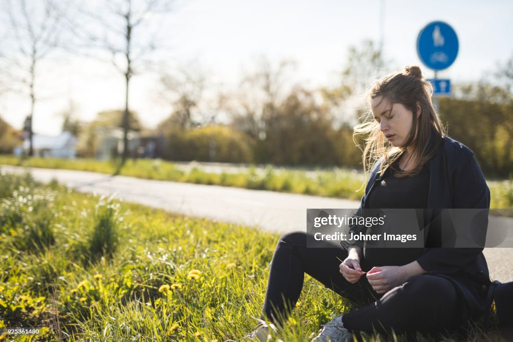 Pregnant woman sitting at roadside