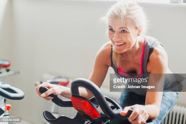 woman exercising on stationary bicycle in gym - images of female bodybuilders stock pictures, royalty-free photos & images