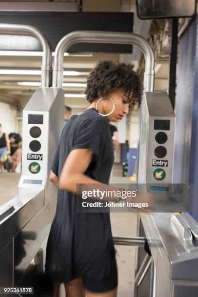 young woman going through turnstile at subway station - torniquete imagens e fotografias de stock