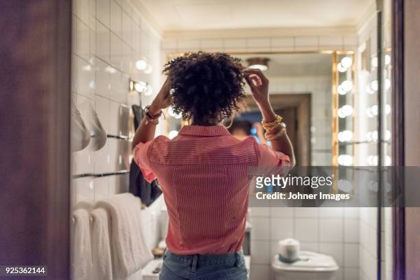 woman preparing hair in bathroom - bathroom mirror fotografías e imágenes de stock