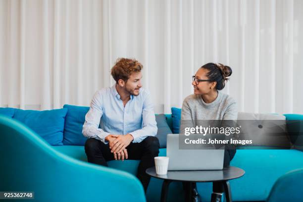 two friends sitting in living room with laptop - meeting room stock-fotos und bilder