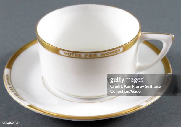 China cup and saucer set, white with gold embellishment at the rim and border, with text insets reading "Votes for Women, " distributed by the...