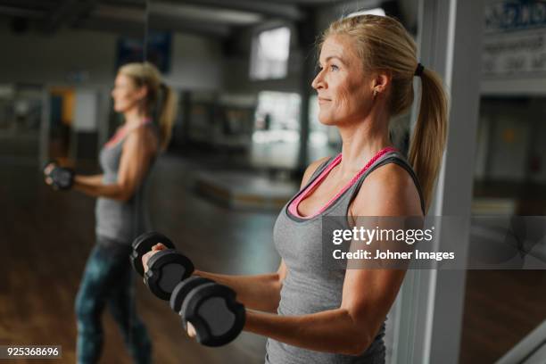 woman exercising with dumbbells in gym - krafttraining stock-fotos und bilder