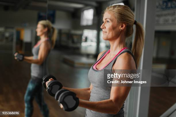 woman exercising with dumbbells in gym - manubrio foto e immagini stock